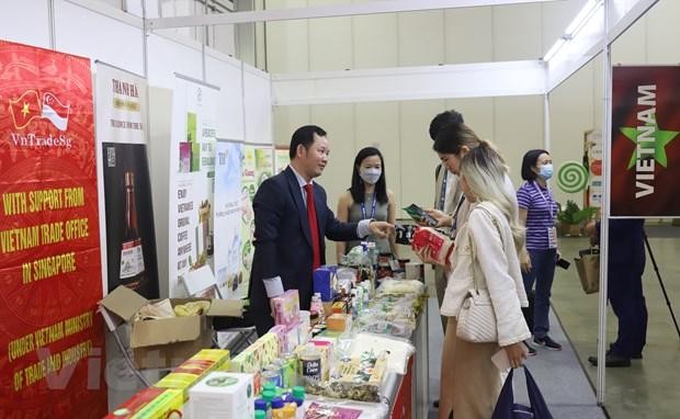 Представитель Торгового представительства Вьетнама в Сингапуре Као Суан Тханг (слева) представляет международным компаниям новые вьетнамские продукты. Фото: VNA