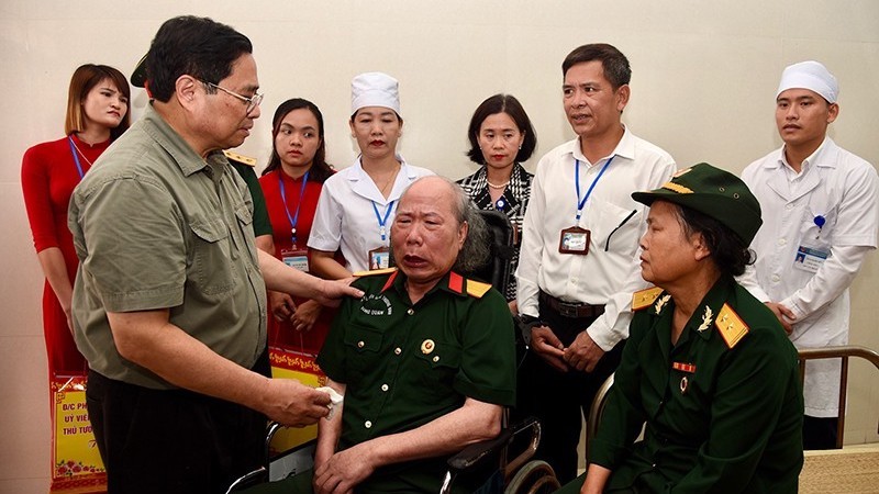 Премьер-министр Фам Минь Тьинь и больные ветераны войны, проходящие лечение в Санаторном центре для инвалидов войны и больных военнослужащих Ньокуан. Фото: Чан Хай