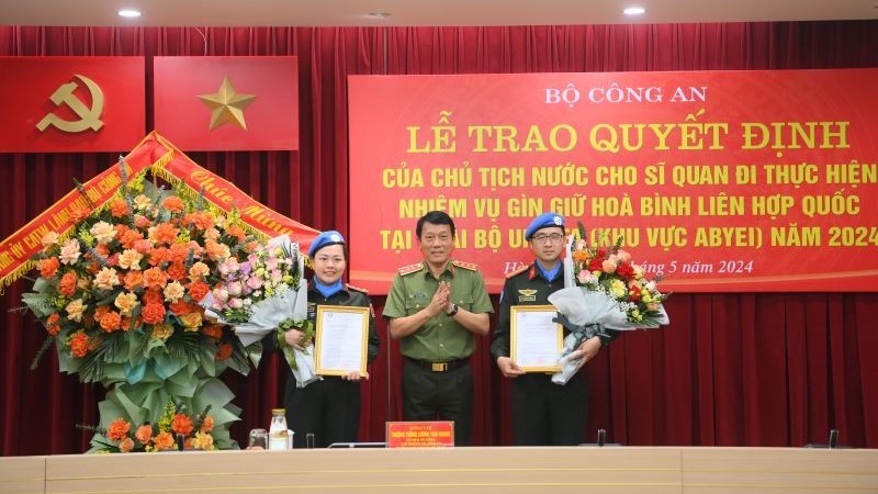 Замминистра общественной безопасности Лыонг Там Куанг вручает вручения решения Президента 2 офицерам.