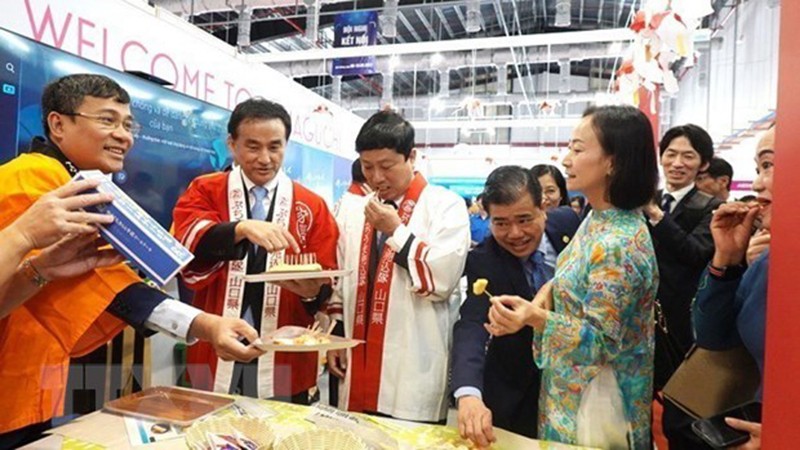 Руководители провинции Биньзыонг и префектуры Ямагути пробуют вьетнамские продукты на ярмарке. Фото: ВИА