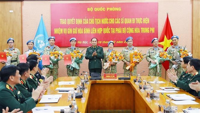 Генерал-лейтенант Фунг Ши Тан вручает решения 4 офицерам, которые будут участвовать в миротворческой миссии, и вручает цветы 4 офицерам, которые завершили свой срок работы. Фото: ВИА