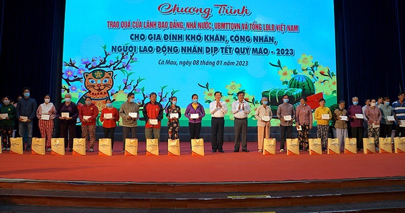 Вице-премьер Ле Минь Кхай и Секретарь Парткома провинции Камау Нгуен Тиен Хай вручают подарки бедным семьям и трудящимся.