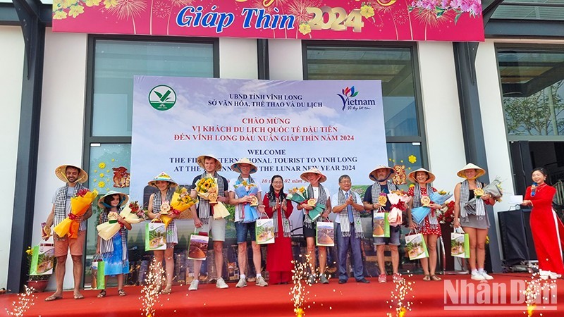 Руководители провинции Виньлонг вручают сувениры первым иностранным туристам.