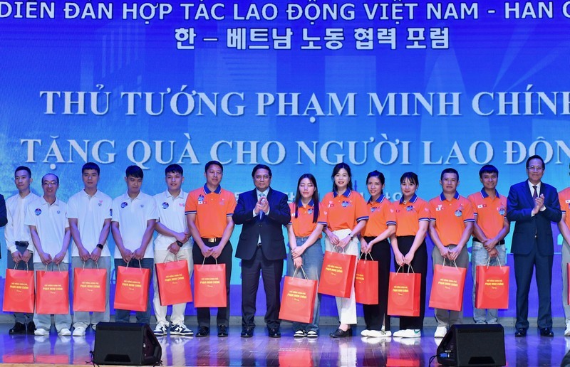 Премьер-министр Фам Минь Тьинь вручает подарки выдающимся вьетнамским трудящимся, работающим в Южной Корее. Фото: Тхань Жанг