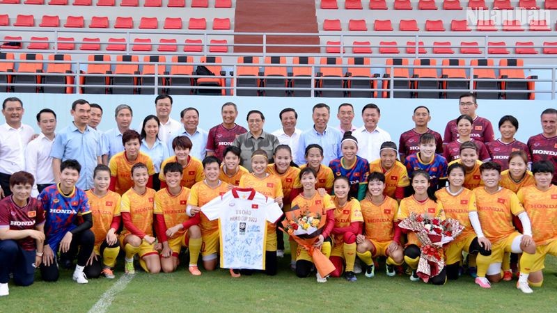 Премьер-министр Фам Минь Тьинь фотографируется на память с женской сборной Вьетнама по футболу. 