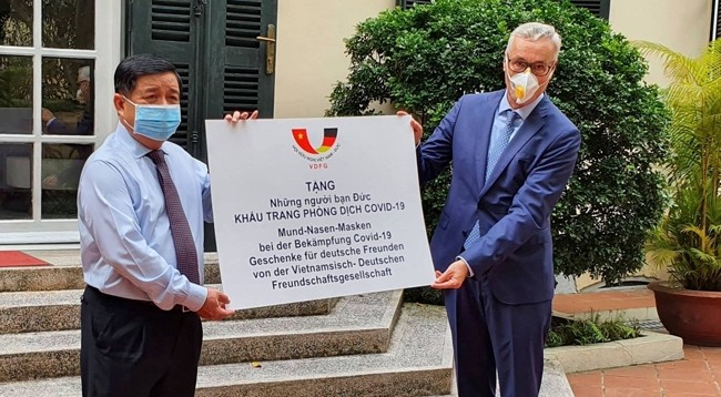 Министр планирования и инвестиций Вьетнама Нгуен Тьи Зунг (слева) символически вручает маски Послу Германии во Вьетнаме Гвидо Хильднеру. Фото: baoquocte.vn