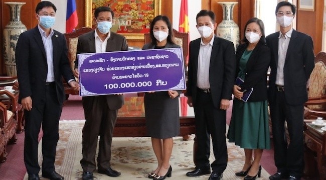 Товарищ Тхонгсаван Вонгсамфан символически вручает 100 млн лаосских кипов посланнику Чинь Тхи Там.