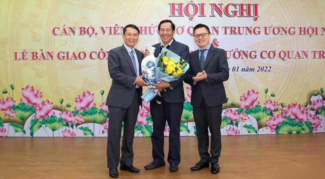 Товарищ Ле Куок Минь и товарищ Нгуен Дык Лой вручают цветы товарищу Тхуан Хыу на церемонии передачи работы.