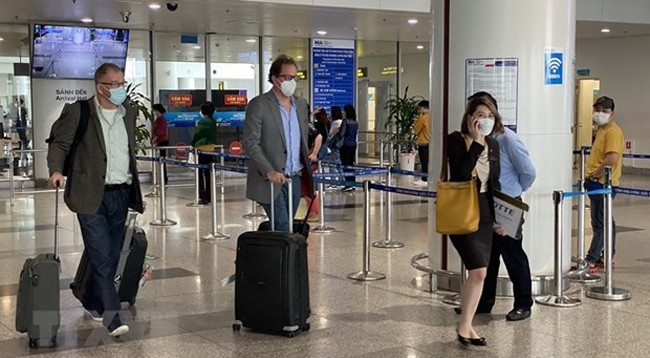 Иностранные гости в аэропорту Нойбай в первый день открытия туризма. Фото: VNA