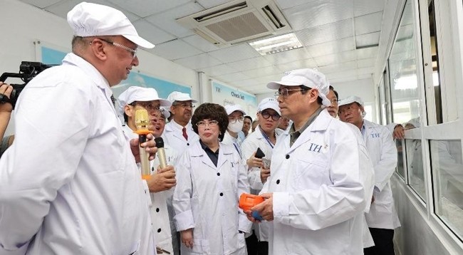 Премьер-министр Фам Минь Тьинь слушает презентацию о технологиях молочного животноводства группы «TH». Фото: Чан Хай