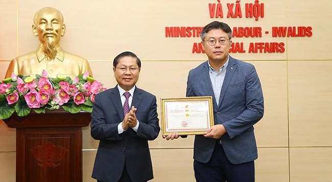 Заместитель министра труда, инвалидов войны и социального обеспечения Ле Тан Зунг вручает памятную медаль г-ну Канг Бюнг Джу.